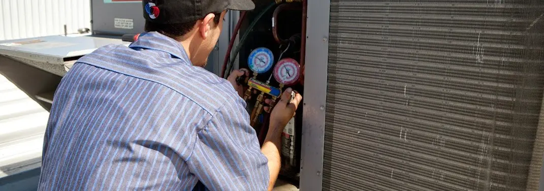 HVAC technician servicing a condenser unit in Paradise